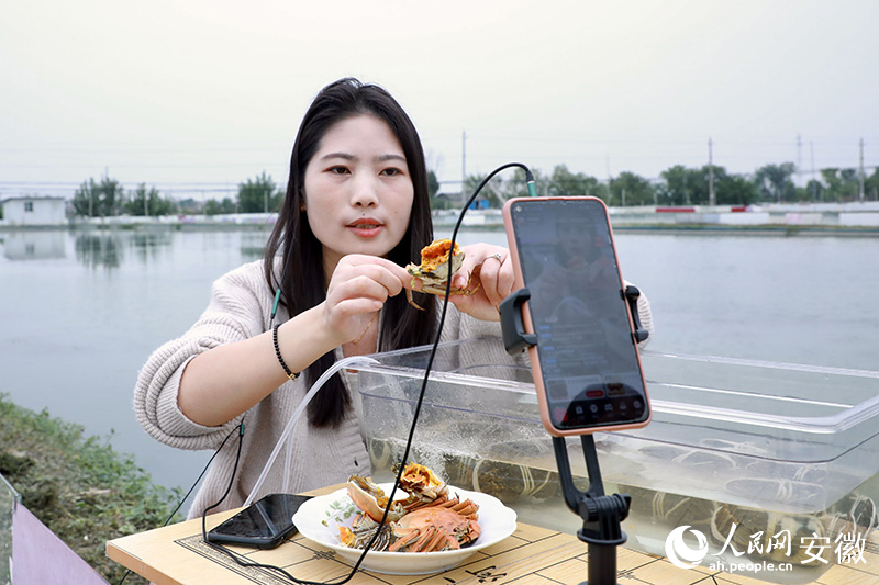 许有为的媳妇宋青霞在塘埂边现场直播带蟹。人民网记者 陶涛摄